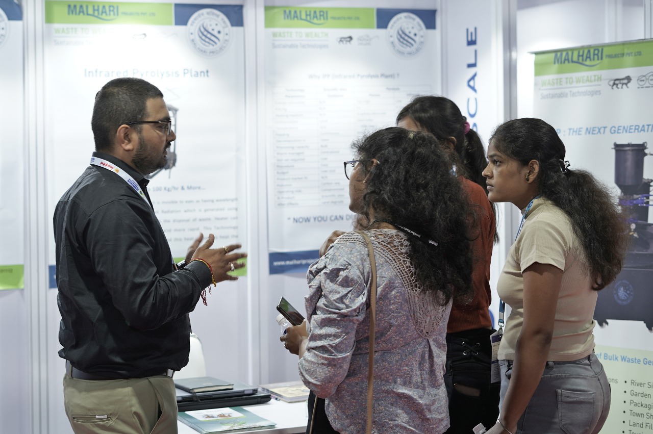 An exhibitor walks three visitors through a pyrolysis plant at his stand.